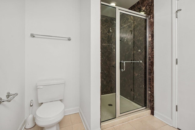 bathroom featuring baseboards, toilet, a stall shower, and tile patterned flooring