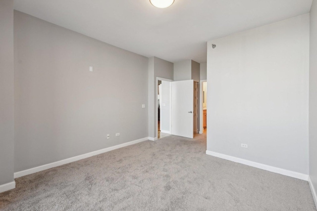 empty room featuring light colored carpet and baseboards