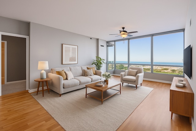 living area with baseboards, visible vents, light wood-style floors, and a ceiling fan
