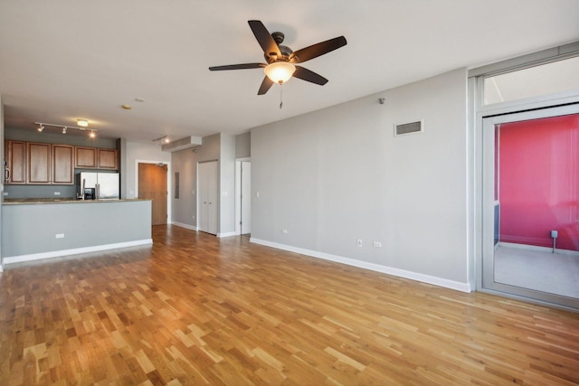unfurnished living room with baseboards, ceiling fan, visible vents, and light wood-style floors