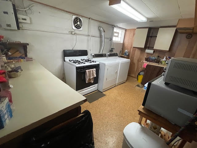 kitchen featuring washing machine and clothes dryer, white cabinetry, and white range with gas stovetop