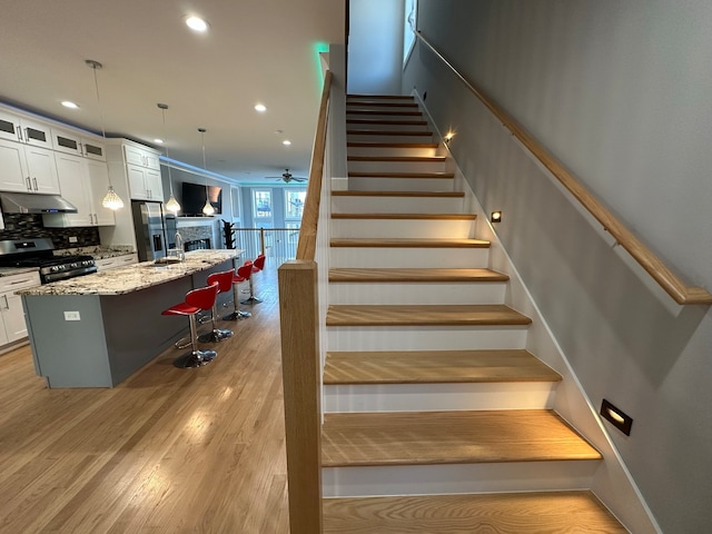 stairs featuring ceiling fan, hardwood / wood-style floors, and sink