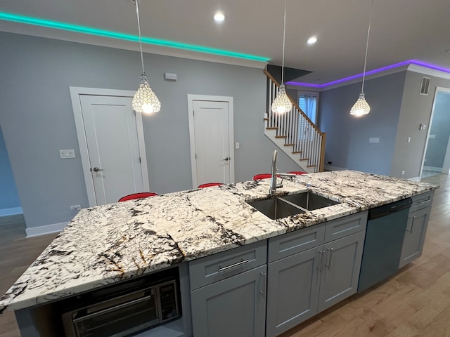 kitchen featuring light stone counters, hardwood / wood-style flooring, sink, an island with sink, and stainless steel dishwasher