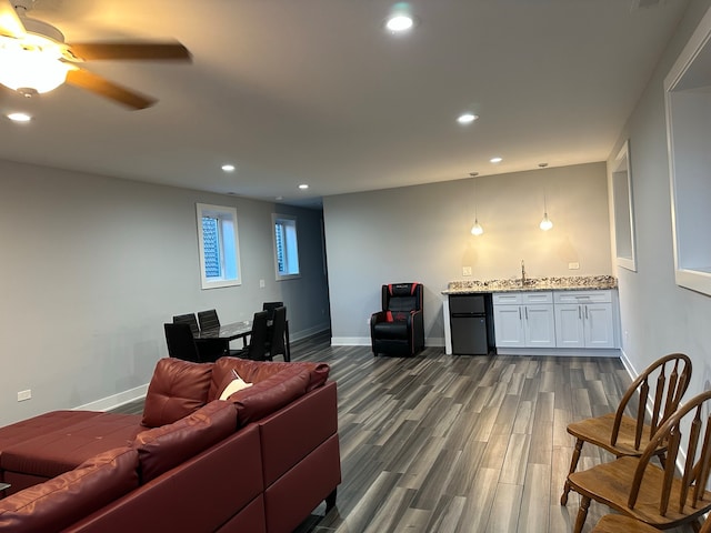 living room with indoor wet bar, dark hardwood / wood-style flooring, and ceiling fan