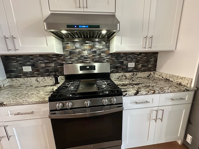 kitchen with light stone counters, stainless steel gas stove, backsplash, white cabinetry, and exhaust hood