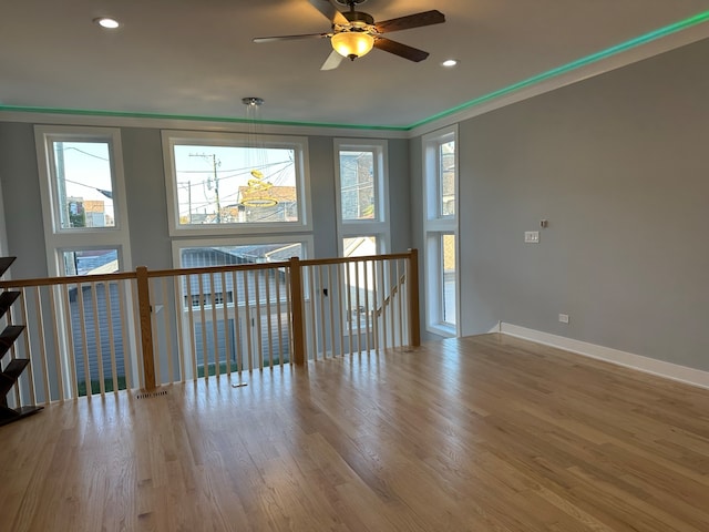 spare room featuring a healthy amount of sunlight, ornamental molding, ceiling fan, and hardwood / wood-style flooring