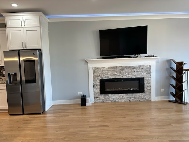 unfurnished living room featuring a stone fireplace, light hardwood / wood-style flooring, and ornamental molding