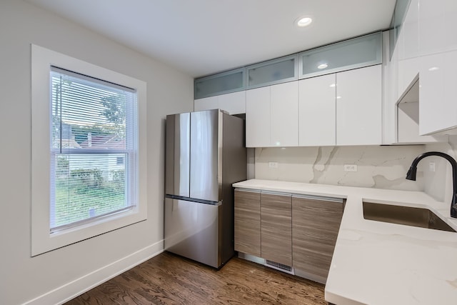 kitchen featuring stainless steel fridge, sink, white cabinetry, dark hardwood / wood-style floors, and light stone countertops