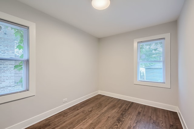 spare room featuring a healthy amount of sunlight and dark hardwood / wood-style flooring