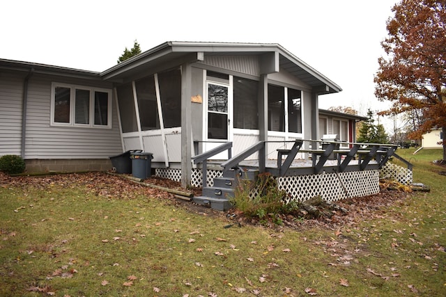 view of side of home featuring a lawn, a sunroom, and a deck