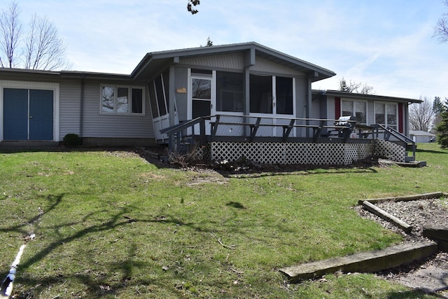 rear view of house with a deck, a sunroom, and a lawn