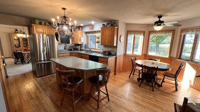 kitchen featuring wood-type flooring, freestanding refrigerator, a sink, and a wainscoted wall