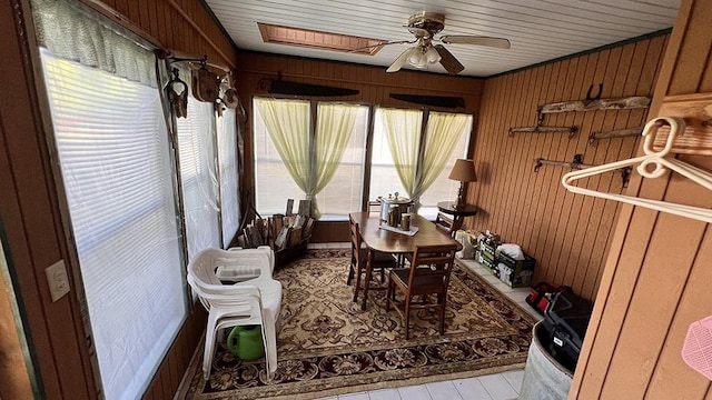 dining room featuring a ceiling fan and wooden walls