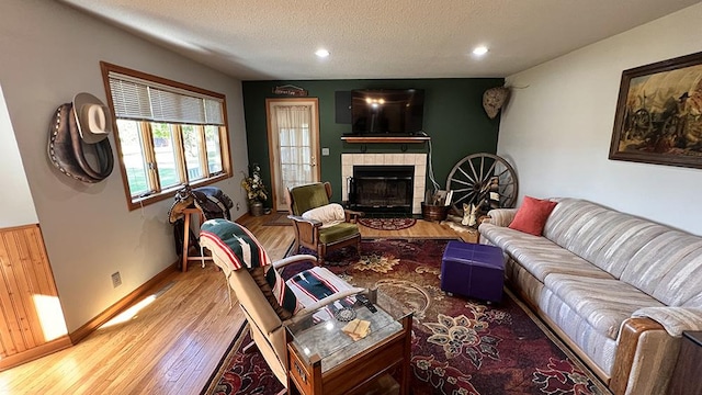 living room featuring wood finished floors, a fireplace, baseboards, recessed lighting, and a textured ceiling