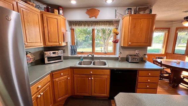 kitchen featuring stainless steel refrigerator, sink, a textured ceiling, and black dishwasher