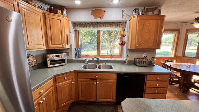 kitchen with freestanding refrigerator, a textured ceiling, a sink, and dishwasher