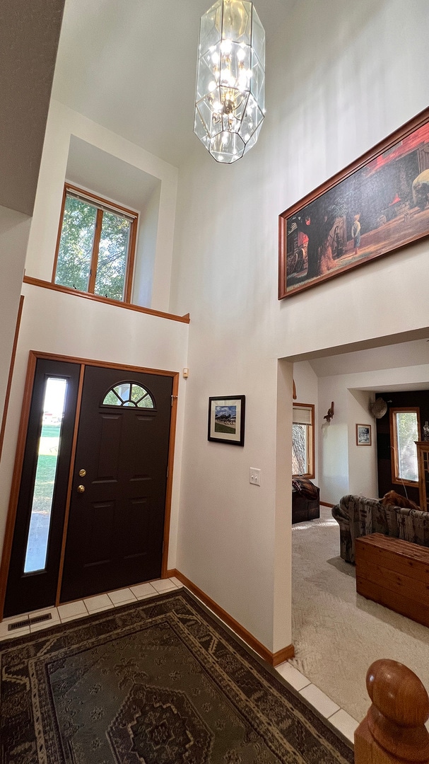 entryway with carpet floors, a high ceiling, and a notable chandelier