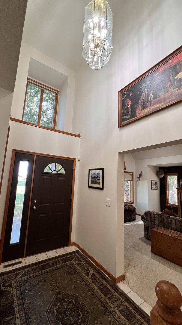 carpeted foyer with baseboards, a chandelier, tile patterned flooring, and a towering ceiling