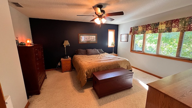 bedroom with ceiling fan, light colored carpet, and a textured ceiling