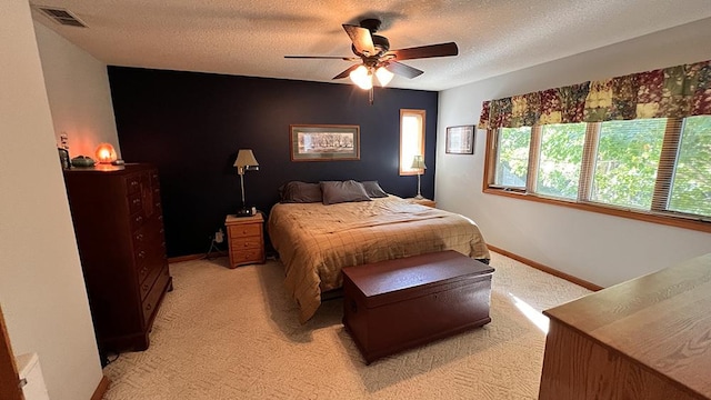 bedroom with ceiling fan, light carpet, a textured ceiling, baseboards, and visible vents