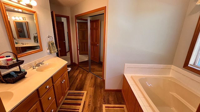 bathroom with vanity, hardwood / wood-style flooring, and a relaxing tiled tub