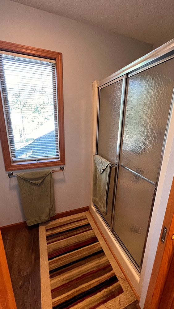 bathroom with walk in shower and hardwood / wood-style floors