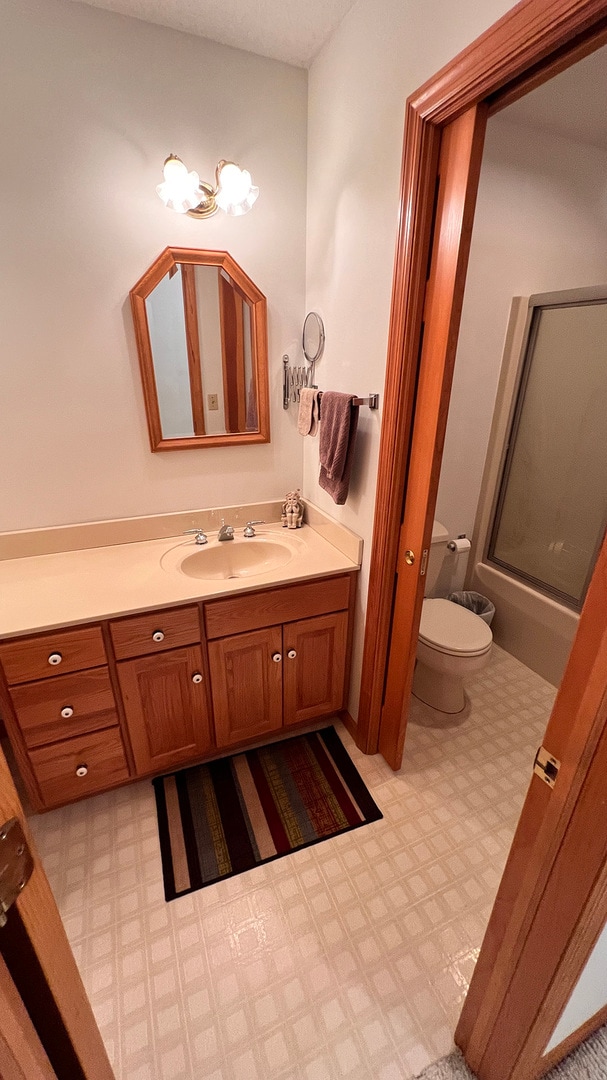 bathroom featuring vanity, toilet, and a shower with door