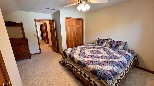 bedroom with a closet, ceiling fan, light colored carpet, and a textured ceiling