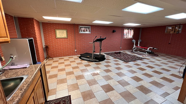 workout room featuring brick wall, a paneled ceiling, and sink