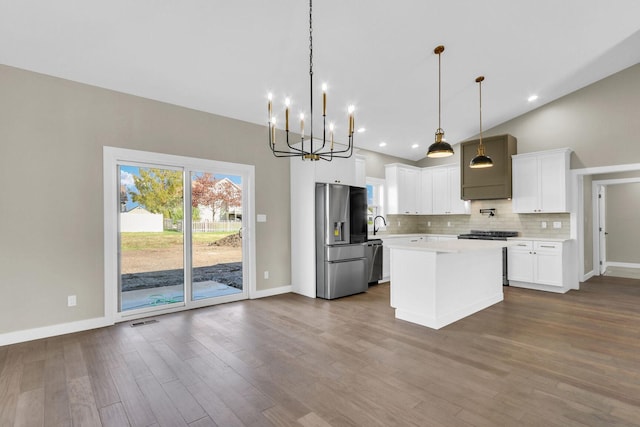 kitchen featuring dark wood-type flooring, white cabinets, vaulted ceiling, decorative light fixtures, and stainless steel appliances