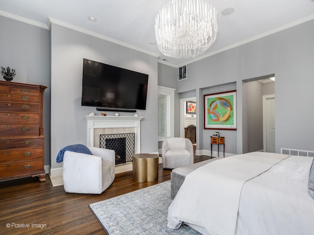 bedroom featuring a notable chandelier, a tile fireplace, dark wood-type flooring, and crown molding