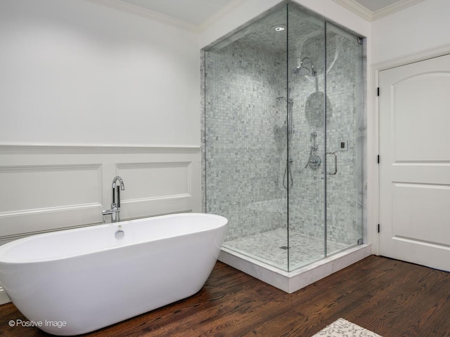 bathroom with a freestanding bath, wood finished floors, crown molding, and a shower stall