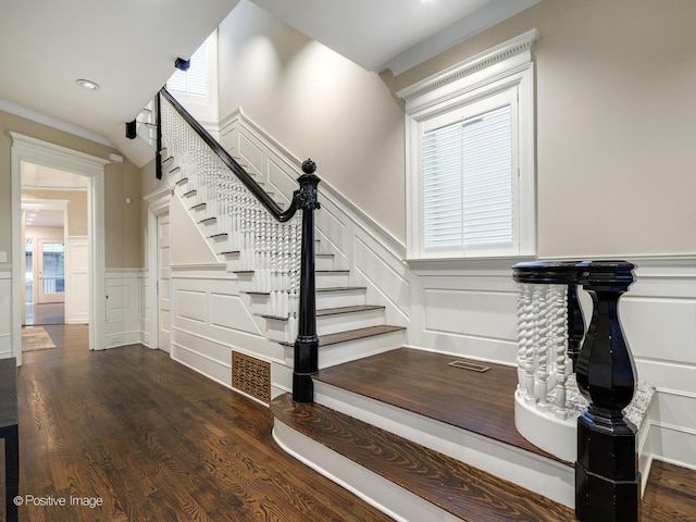 staircase with a decorative wall, wainscoting, visible vents, and wood finished floors