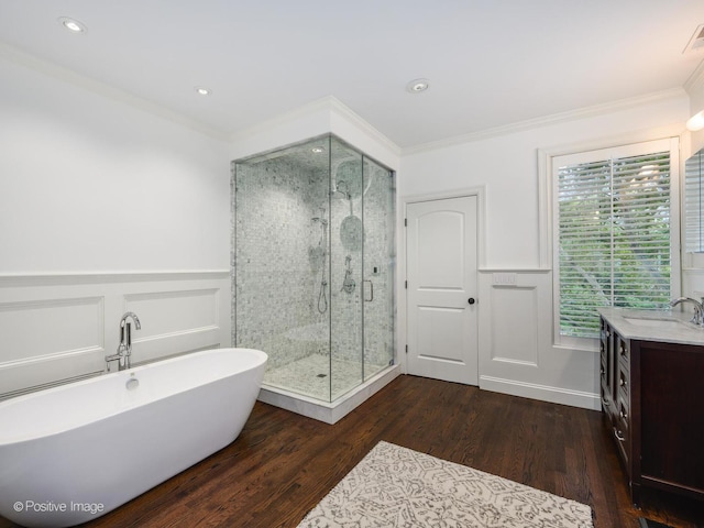 bathroom featuring a wainscoted wall, crown molding, wood finished floors, vanity, and a stall shower