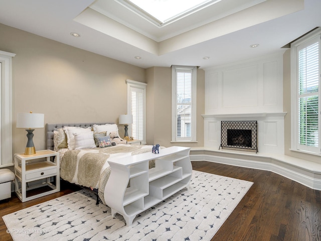 bedroom featuring multiple windows, wood-type flooring, and a tile fireplace