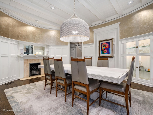 dining room featuring dark hardwood / wood-style floors, beam ceiling, a fireplace, a high ceiling, and wooden ceiling