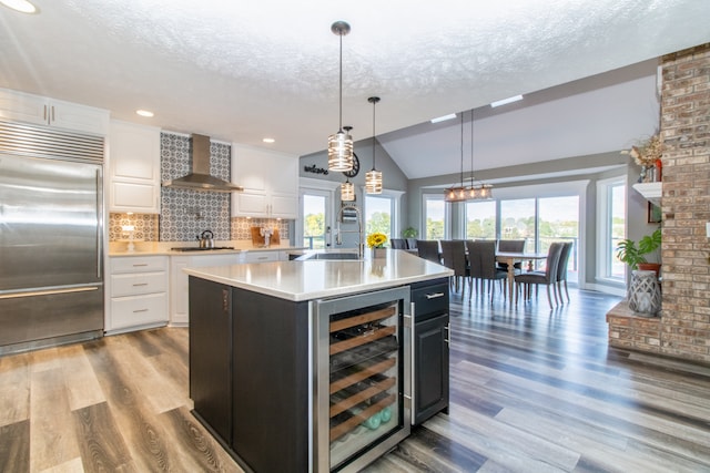 kitchen featuring white cabinets, wall chimney range hood, wine cooler, and stainless steel appliances