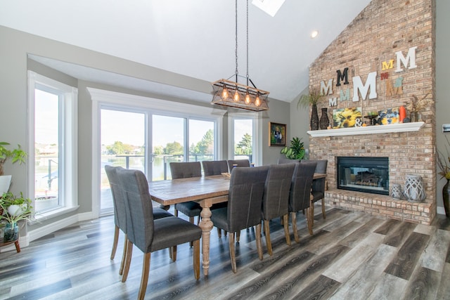 dining room featuring hardwood / wood-style floors, a brick fireplace, and high vaulted ceiling