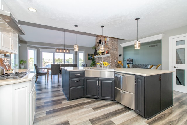 kitchen featuring pendant lighting, white cabinets, light wood-type flooring, and wall chimney range hood