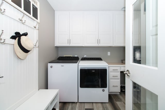 clothes washing area with washing machine and clothes dryer, dark wood-type flooring, and cabinets