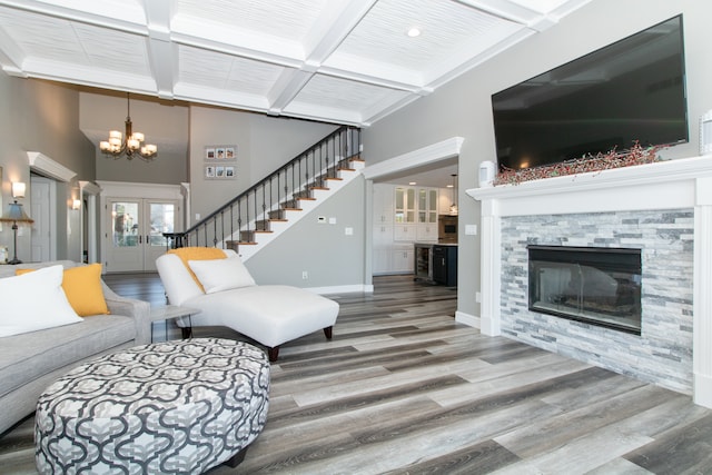 living room with a notable chandelier, a fireplace, beam ceiling, and hardwood / wood-style flooring