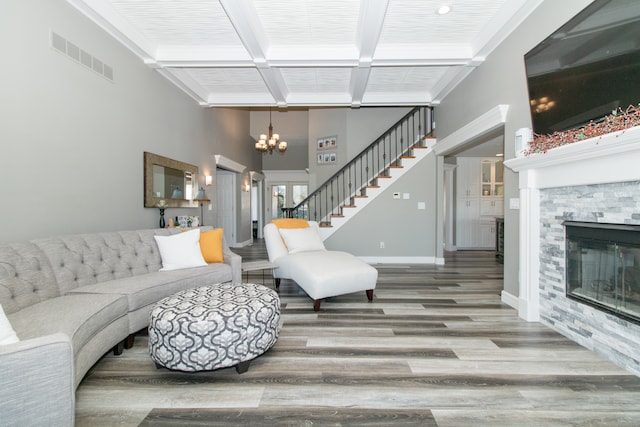 living room with wood-type flooring, a fireplace, a chandelier, and beamed ceiling