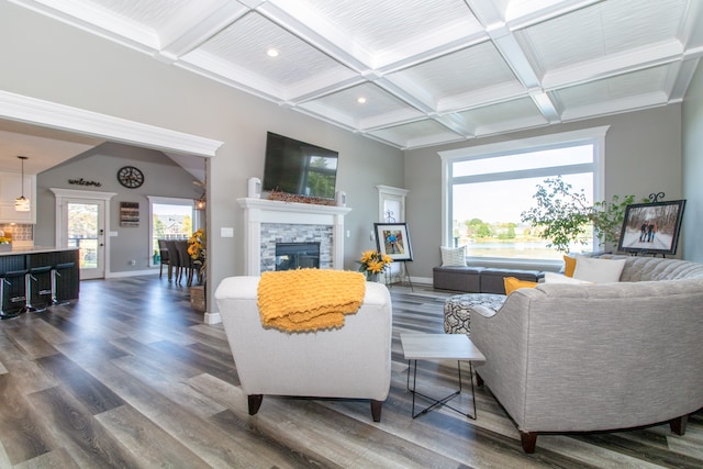 living room featuring dark hardwood / wood-style flooring, beamed ceiling, coffered ceiling, a fireplace, and crown molding