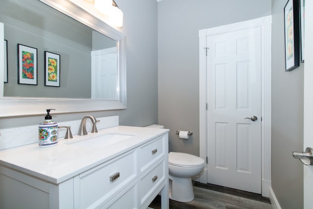 bathroom with wood-type flooring, vanity, and toilet