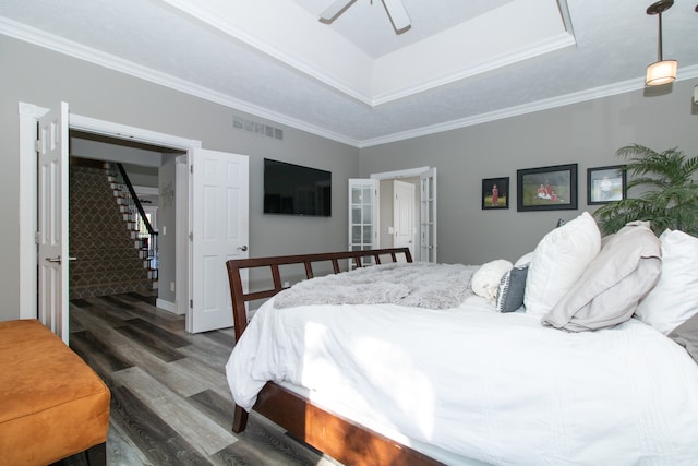 bedroom featuring ceiling fan, ornamental molding, a raised ceiling, and dark wood-type flooring