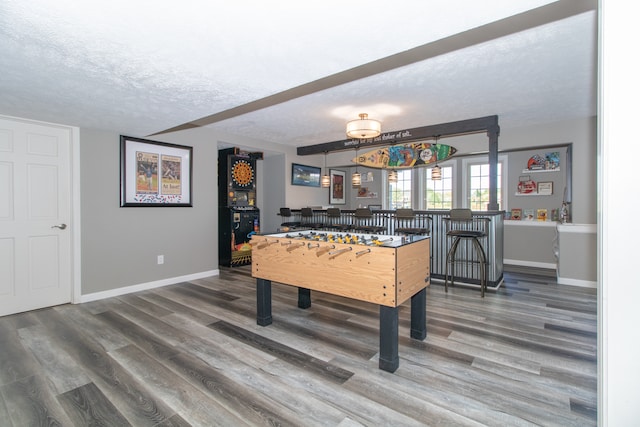 playroom with a textured ceiling, bar area, and hardwood / wood-style flooring