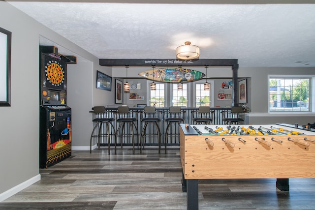 game room featuring a textured ceiling, bar area, and dark hardwood / wood-style flooring