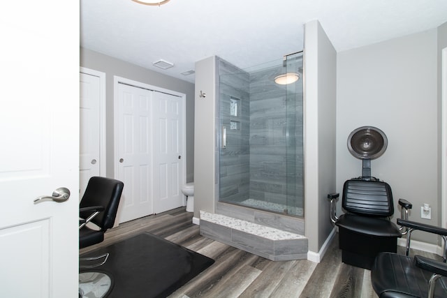 bathroom with a shower with door, toilet, and hardwood / wood-style flooring