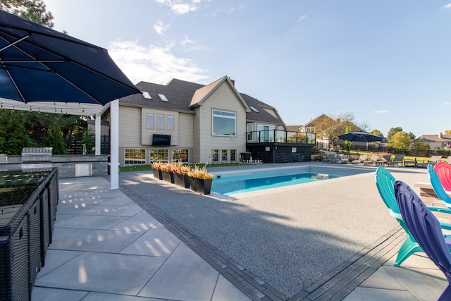 view of swimming pool featuring an outdoor kitchen, a grill, and a patio area