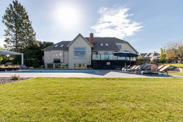 rear view of property with a lawn, a pool, and a patio area